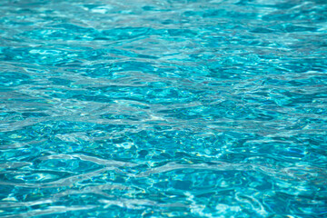 Water background. Blue water, ripples and highlights. Texture of water surface and tiled bottom.