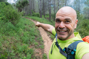 Man takes a selfie in the forest, pointing the path on background
