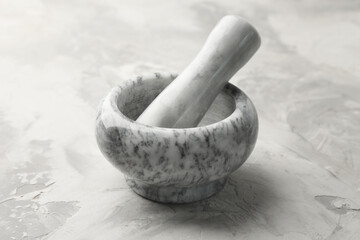 Marble mortar and pestle on grey textured table, closeup