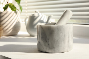 Marble mortar and pestle on windowsill indoors, closeup