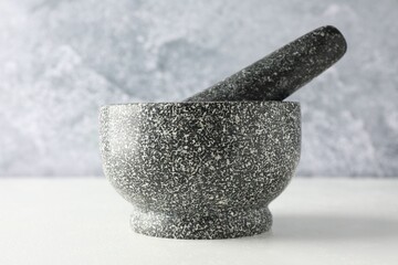 Stone mortar and pestle on white table, closeup