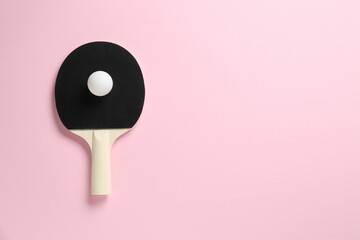 Ping pong racket and ball on pink background, top view. Space for text