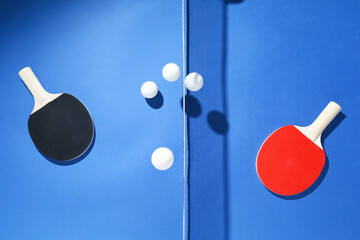 Ping pong rackets, balls and net on blue background, flat lay