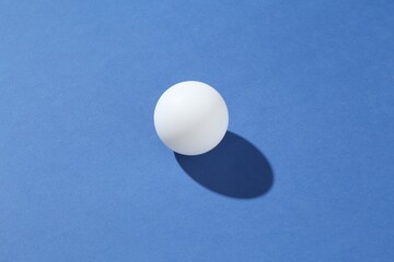 One ping pong ball on blue background