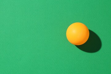 One ping pong ball on green background, top view. Space for text