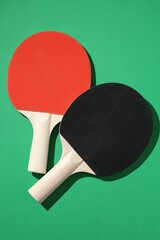 Ping pong rackets on green background, top view