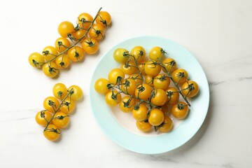 Ripe yellow cherry tomatoes on white marble table, flat lay
