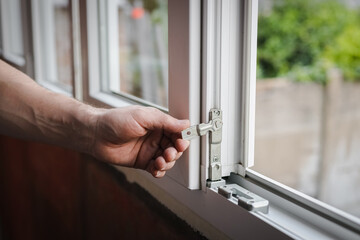 One young worker installs fittings on a plastic window frame.