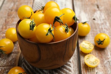 Many fresh yellow tomatoes on wooden table, closeup