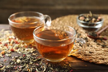 Refreshing herbal tea and dry leaves on wooden table, closeup