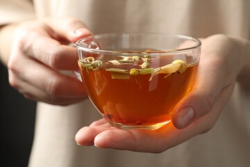 Woman with glass cup of aromatic herbal tea, closeup