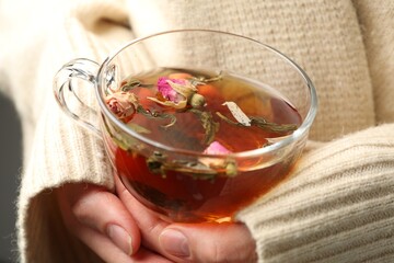Woman with glass cup of aromatic herbal tea, closeup