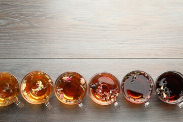 Aromatic herbal tea in glass cups on wooden table, flat lay. Space for text