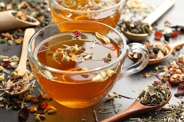 Aromatic herbal tea and dry leaves on grey table, closeup