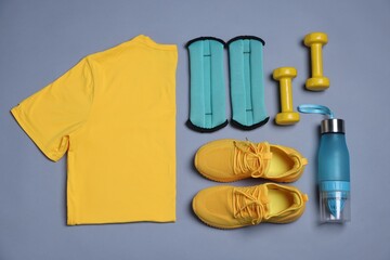 Sportswear, ankle weights, water bottle and dumbbells on grey background, flat lay