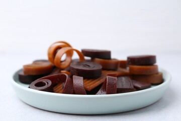 Tasty fruit leather rolls on white table, closeup. Space for text