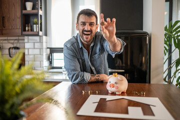 Man saving money for buying a house using piggy bank