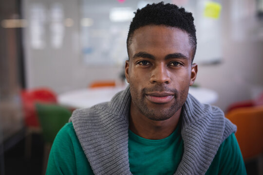 African American man looking at camera in modern meeting room with table and colorful chairs