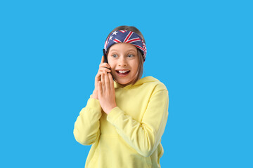 Little girl talking by mobile phone on blue background