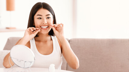 Toothcare And Oral Treatment Concept. Smiling confident asian female vlogger using dental floss at...