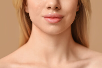 Young woman with beautiful lips on brown background, closeup