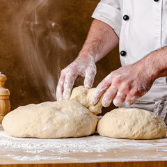 Obraz premium An experienced chef kneads a dough ball covered in flour on a wooden table for baking bread.