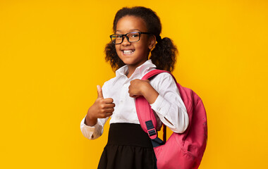African American School Girl Gesturing Thumbs Up Posing With Backpack And Smiling Over Yellow...