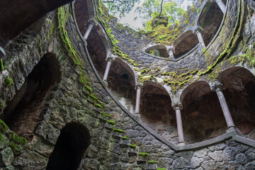 An evocative upward view from inside a deep stone corridor. Rough walls and layered niches guide...