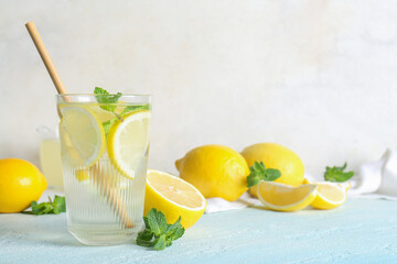 Glass of fresh lemonade with mint and fruits on light blue table