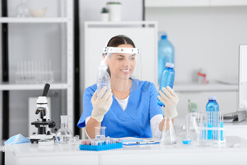 Fototapeta premium Happy female young scientist with professional glassware examining water quality in research laboratory