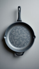 A black skillet with a speckled interior, resting on a gray background.