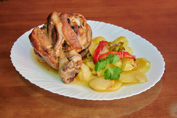 A plate of meat and potatoes with a green herb on the side. The meat is cut into small pieces and is served on a white plate