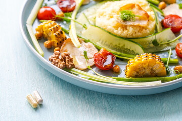 A plate with delicious and healthy food: couscous with vegetables and a plate with pills. Concept: Pills or healthy food.