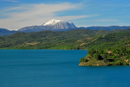 Water cycle, reservoir in Catalonia with snow-capped peaks of the Pyrenees and cirrostratus clouds in blue sky - Powered by Adobe