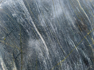 Close-up of a dark rock surface with white and yellow stripes.
