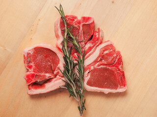 Fresh lamb loin chops and fresh green rosemary herb on a wooden board. Expensive high quality meat...