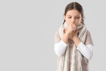 Sick girl with scarf coughing on light background