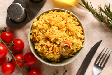 Bowl of tasty pilaf with cherry tomatoes and rosemary on table
