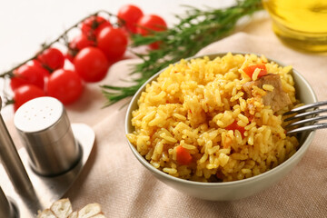 Bowl with tasty pilaf and ingredients on table, closeup