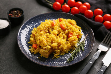 Plate of tasty pilaf with cherry tomatoes and spices on black background, closeup