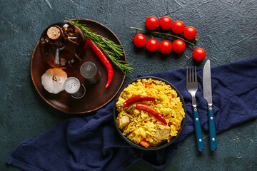 Bowl with tasty pilaf and ingredients on dark background