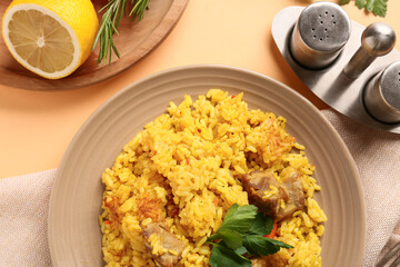 Plate of tasty pilaf with parsley and lemon on orange background, closeup