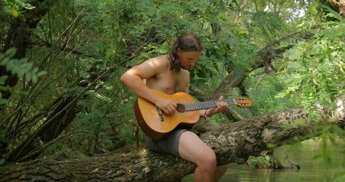 Playing the guitar on a tree above a river