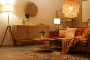 Interior of stylish living room with brown sofa, coffee table and glowing lamps at evening