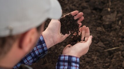 Fertile soil in male hands of farmer. Male hands hold fertile land in field. Organic soil in hands...