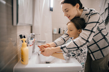 Mother teaching son handwashing in bathroom sink