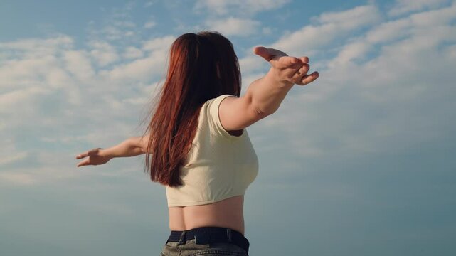 Happy girl meditate looking sky with raised hands. Happiness under sky. Faith in God. Young woman enjoys tranquility in nature, praying against sky, summer park. Young woman freedom concept. Dream fly