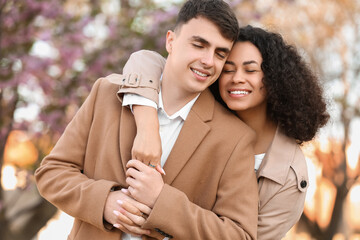 Beautiful young happy couple hugging in park on spring day