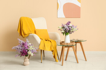 Interior of living room with armchair, tables and lilac flowers in vases