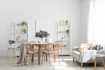 Interior of room with dining table, sofa and lilac flowers in vases